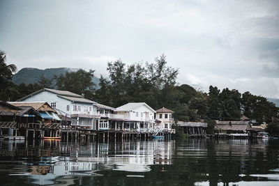 Houses by lake and buildings against sky