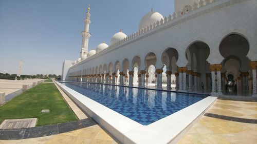 View of swimming pool by building against clear sky