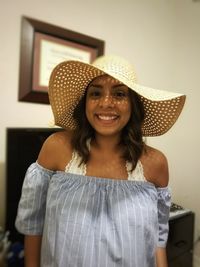 Portrait of smiling young woman standing against wall