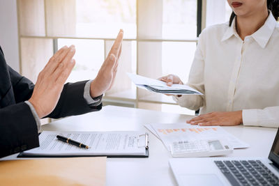 Midsection of client paying money to agent at desk in office