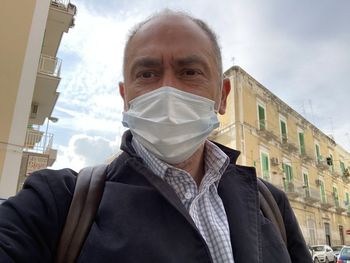 Portrait of man in front of built structure against sky