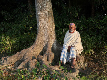 Portrait of man sitting on tree base 