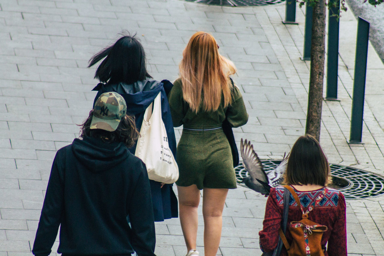 REAR VIEW OF WOMEN WALKING WITH UMBRELLA ON WALKWAY