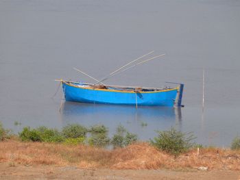 Abandoned boat moored on shore against sky