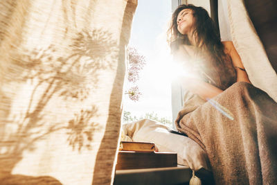 Young woman sitting on bed at home