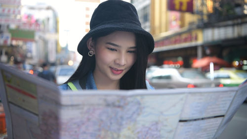 Portrait of smiling young woman holding umbrella in city