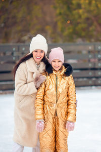 Portrait of smiling mother and daughter standing outdoors