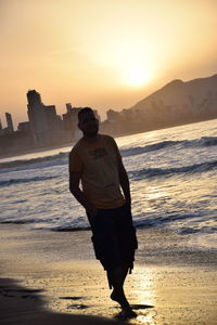 Full length of man standing on beach during sunset