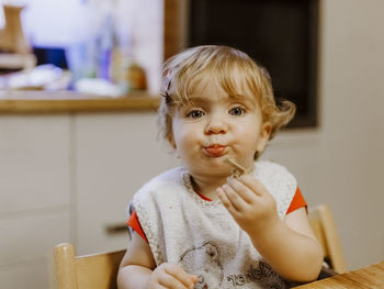 Portrait of cute baby girl sitting at home