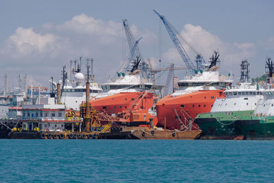 Cranes at harbor against sky