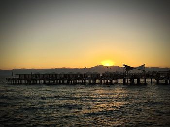 Silhouette of pier over sea during sunset