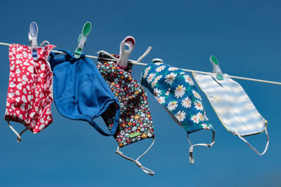 Low angle view of clothes hanging against blue sky