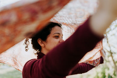 Woman looking away holding scarf while standing outdoors