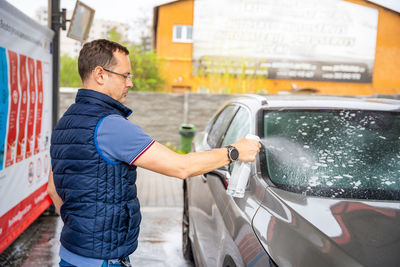 Side view of man standing in car