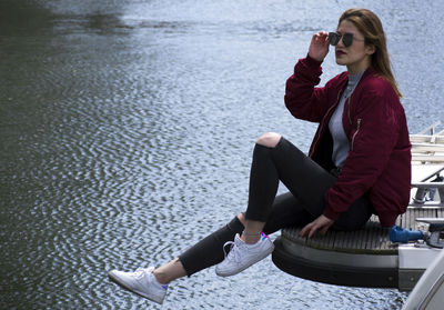 Full length of woman sitting by water