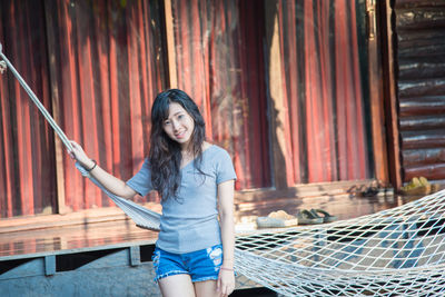 Portrait of young woman standing by hammock