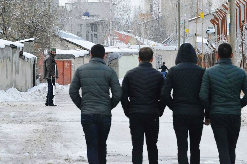 REAR VIEW OF PEOPLE ON SNOW COVERED CITY