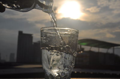 Close-up of drink in glass against sky during sunset