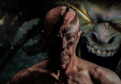 Portrait of bald man with face paint against spooky background