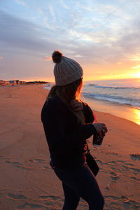 Rear view of woman on beach during sunset