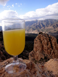 Close-up of beer glass on rock against sky