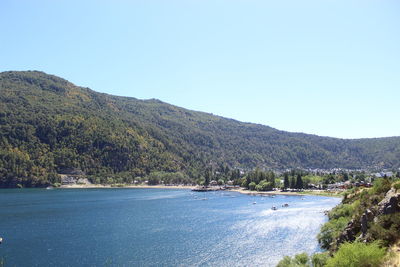 Scenic view of sea and mountains against clear blue sky