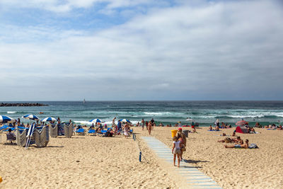 Crowd at beach against sky