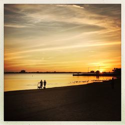 Silhouette people on beach against sky during sunset