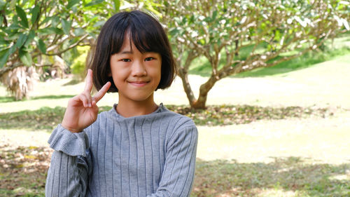 Portrait of young woman standing against trees