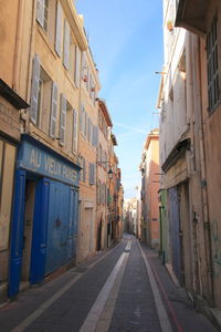 Empty road amidst buildings against sky