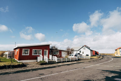 Road by buildings against sky