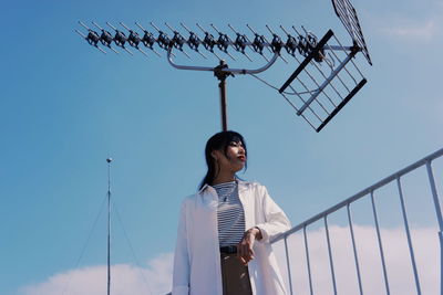 Low angle view of woman looking away against sky