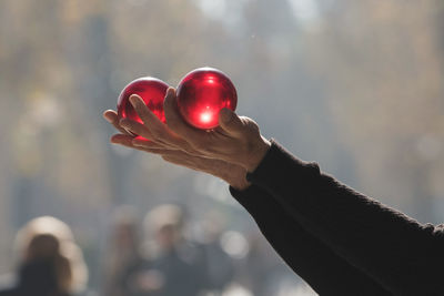 Cropped hands holding red balls outdoors