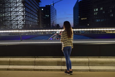 Rear view of woman using mobile phone at night