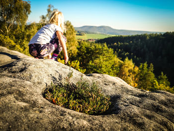 Man sitting on rock against mountains