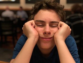 Portrait of bored teenage boy sitting in restaurant