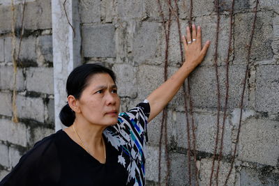 Mature woman wearing casuals while standing by wall