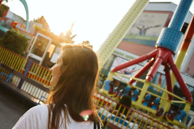 Rear view of woman standing at amusement park during sunset