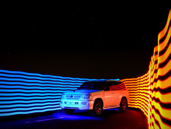 Car on illuminated road against sky at night