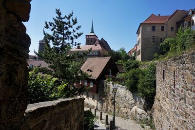 Houses by trees and buildings against sky