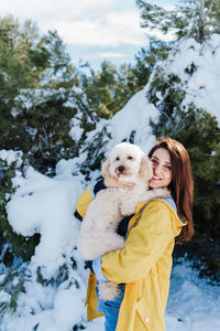 Portrait of smiling woman with dog in snow