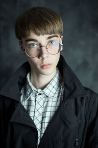 Portrait of young man wearing eyeglasses against wall