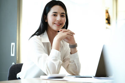 Portrait of smiling young woman sitting on table