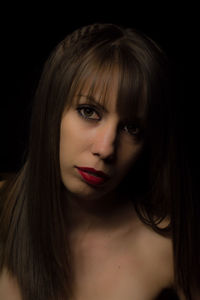 Close-up portrait of young woman over black background