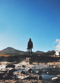 Man on shore against clear blue sky