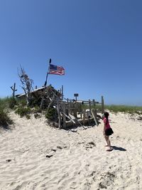 Full length of girl wearing mask standing on beach against sky