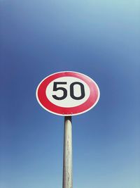 Low angle view of speed limit sign against clear blue sky