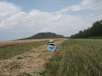 Rear view of woman standing on field against sky