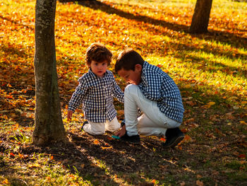 Portrait of boy with brother playing in park during autumn