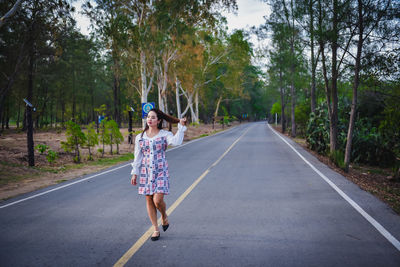 Woman standing on road amidst trees